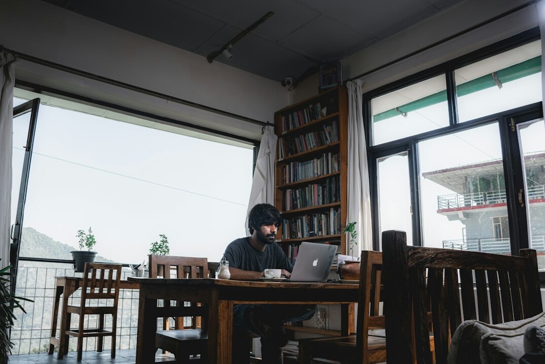 person coding on laptop in cafe